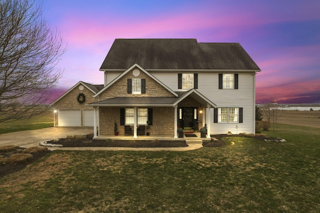 view of front of house with a garage, a yard, and a porch