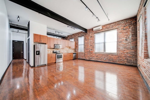 kitchen featuring hardwood / wood-style floors, an AC wall unit, beam ceiling, stainless steel appliances, and brick wall