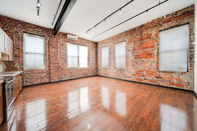 interior space with sink, rail lighting, brick wall, a wall unit AC, and light hardwood / wood-style floors