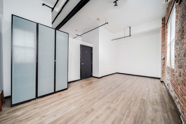 unfurnished bedroom featuring light hardwood / wood-style flooring and brick wall