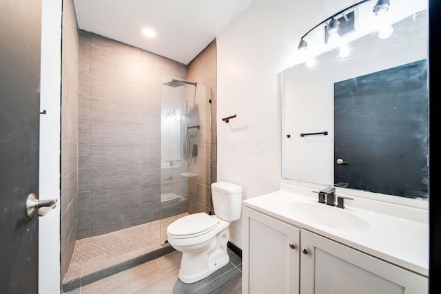 bathroom with a tile shower, vanity, and toilet