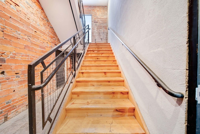 stairs featuring tile patterned floors and brick wall