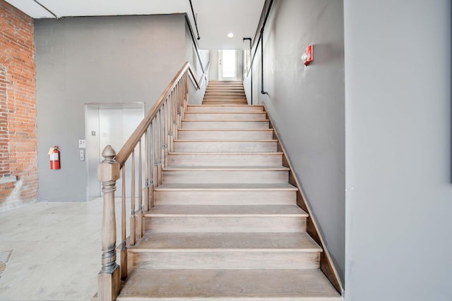 staircase featuring brick wall and a high ceiling