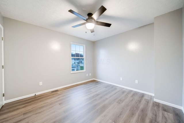 spare room with ceiling fan, light hardwood / wood-style floors, and a textured ceiling