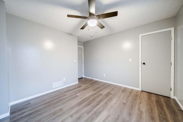 unfurnished room with ceiling fan, a textured ceiling, and light wood-type flooring