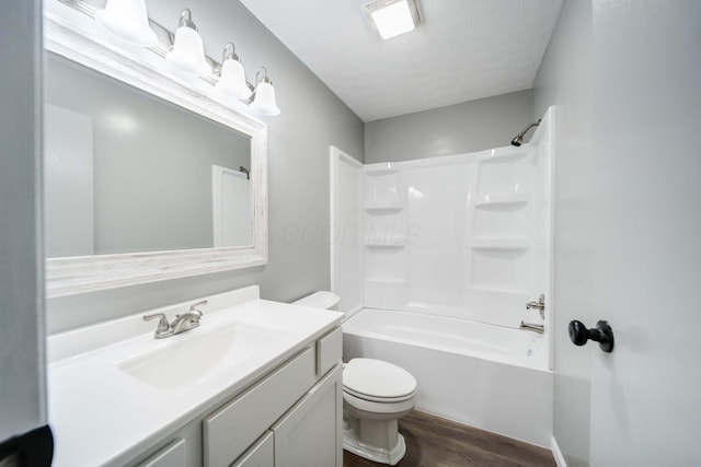 full bathroom featuring wood-type flooring, a textured ceiling, toilet, vanity, and shower / bathtub combination