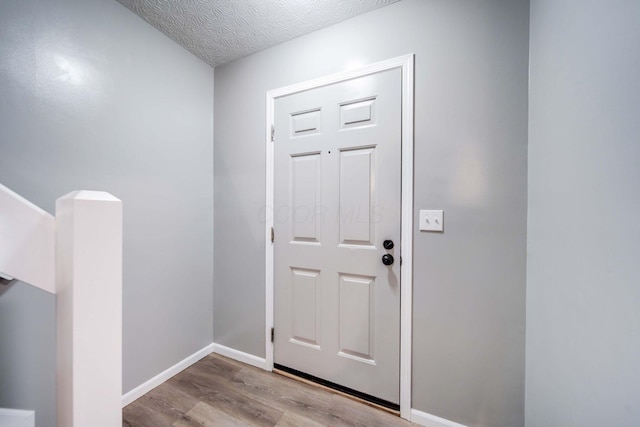 doorway with a textured ceiling and light wood-type flooring