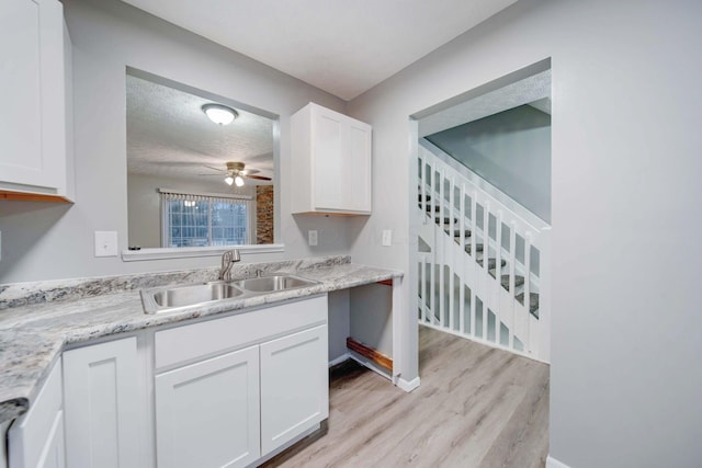 kitchen with ceiling fan, sink, light hardwood / wood-style floors, a textured ceiling, and white cabinets