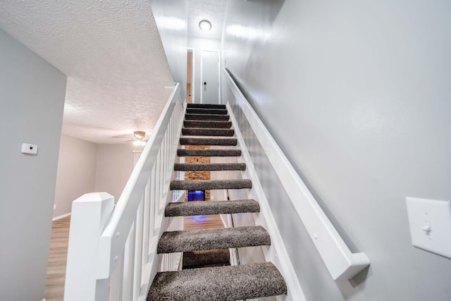 staircase featuring hardwood / wood-style flooring and a textured ceiling