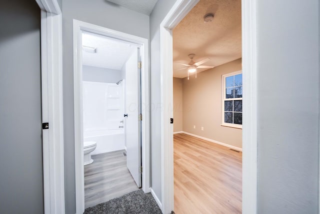 hall featuring a textured ceiling and light wood-type flooring