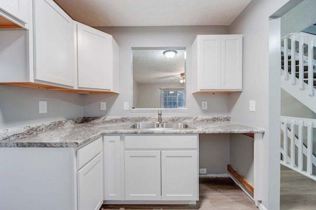 kitchen with white cabinetry, sink, ceiling fan, light hardwood / wood-style floors, and a textured ceiling