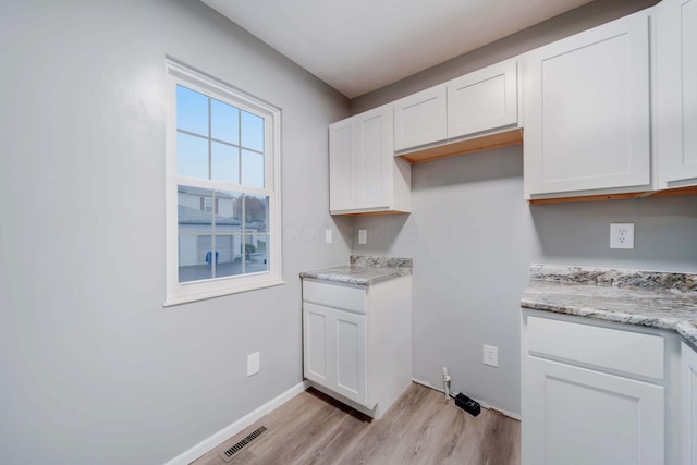 kitchen featuring light stone counters, white cabinetry, and light hardwood / wood-style flooring