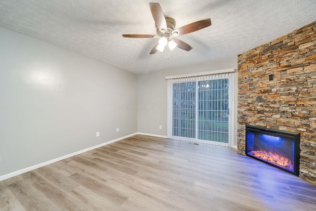 unfurnished living room featuring a fireplace, ceiling fan, light wood-type flooring, and a textured ceiling