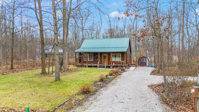 log-style house featuring a shed, covered porch, and a front yard