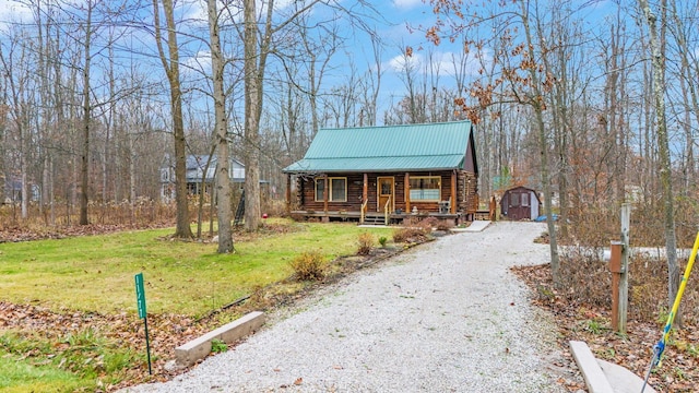 cabin with covered porch, an outbuilding, a garage, and a front lawn