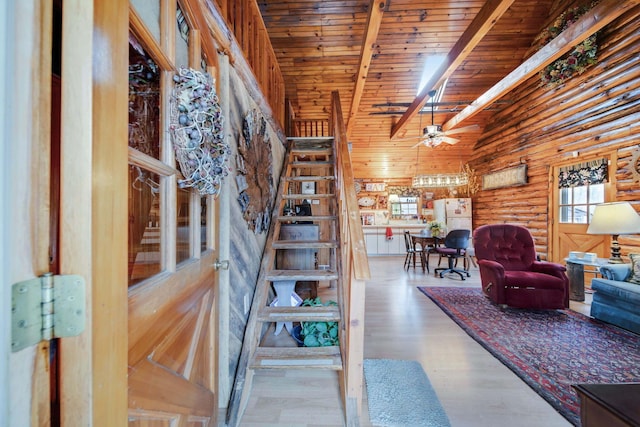 living room featuring light hardwood / wood-style flooring, ceiling fan, log walls, beam ceiling, and wood ceiling