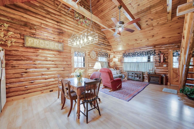 dining space with a healthy amount of sunlight, light hardwood / wood-style floors, rustic walls, and high vaulted ceiling