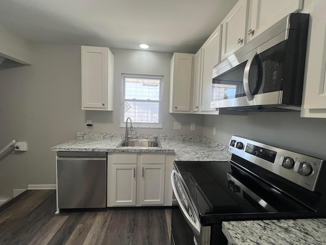 kitchen with light stone counters, dark wood-style floors, stainless steel appliances, white cabinetry, and a sink