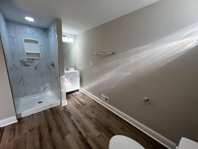 full bathroom featuring a marble finish shower, wood finished floors, vanity, and toilet