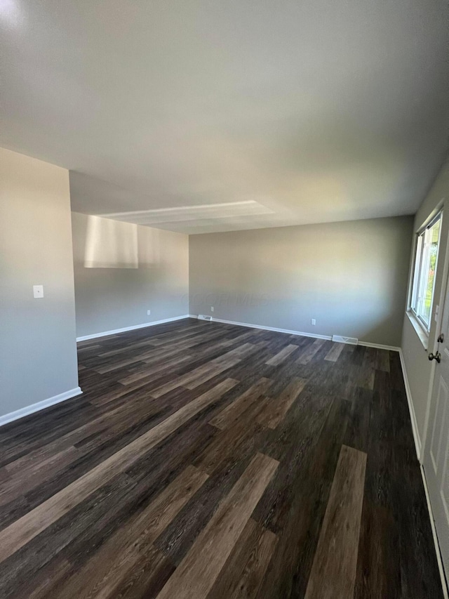 spare room featuring dark wood-style floors and baseboards