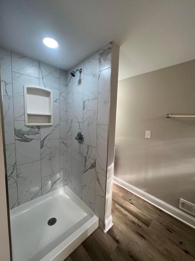 bathroom featuring visible vents, a shower stall, baseboards, and wood finished floors