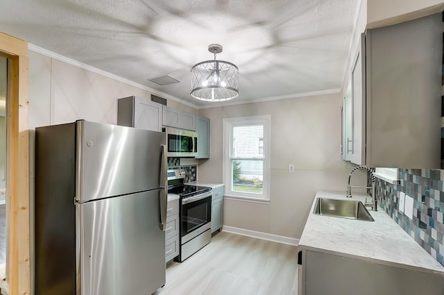 kitchen featuring sink, gray cabinetry, crown molding, tasteful backsplash, and appliances with stainless steel finishes