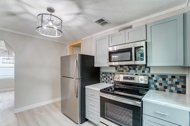 kitchen featuring appliances with stainless steel finishes, tasteful backsplash, hanging light fixtures, ornamental molding, and an inviting chandelier