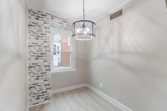 unfurnished dining area with a chandelier and light hardwood / wood-style floors