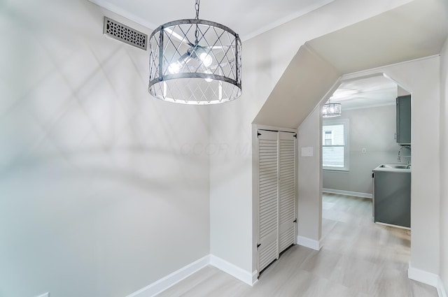 corridor with a chandelier, sink, and light wood-type flooring