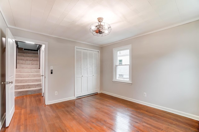 unfurnished bedroom with crown molding, hardwood / wood-style floors, and a closet