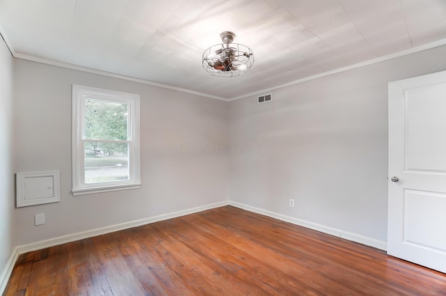 empty room with hardwood / wood-style flooring, ornamental molding, and a chandelier