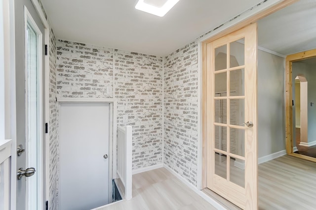 unfurnished room featuring light hardwood / wood-style flooring and brick wall