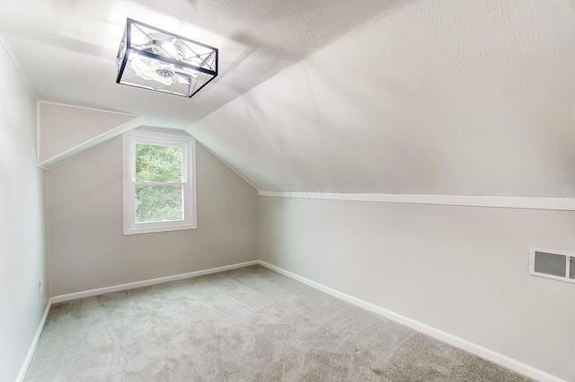 bonus room with lofted ceiling, a textured ceiling, and carpet