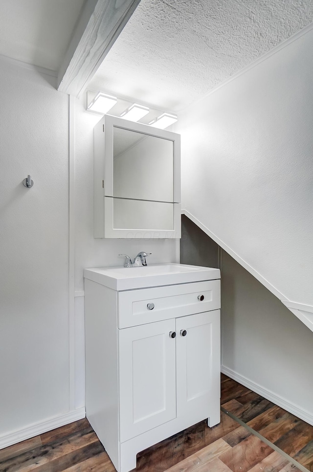 bathroom featuring vaulted ceiling, vanity, hardwood / wood-style floors, and a textured ceiling