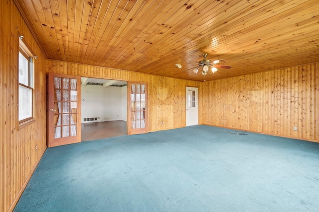 unfurnished room featuring carpet floors, ceiling fan, wooden ceiling, and wood walls