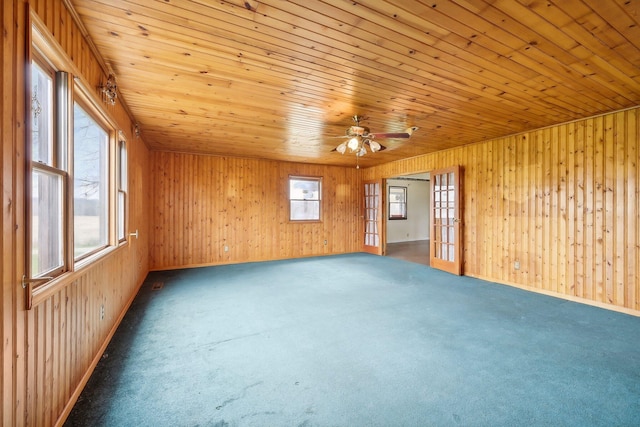 carpeted spare room with wooden walls and wooden ceiling