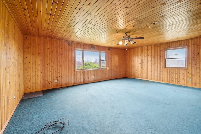 carpeted empty room featuring wooden walls and wood ceiling