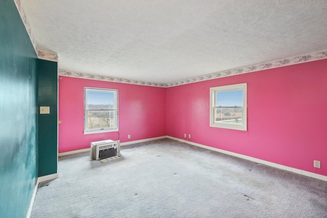 carpeted empty room featuring a wall mounted air conditioner and a textured ceiling