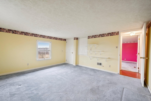 carpeted empty room with a textured ceiling