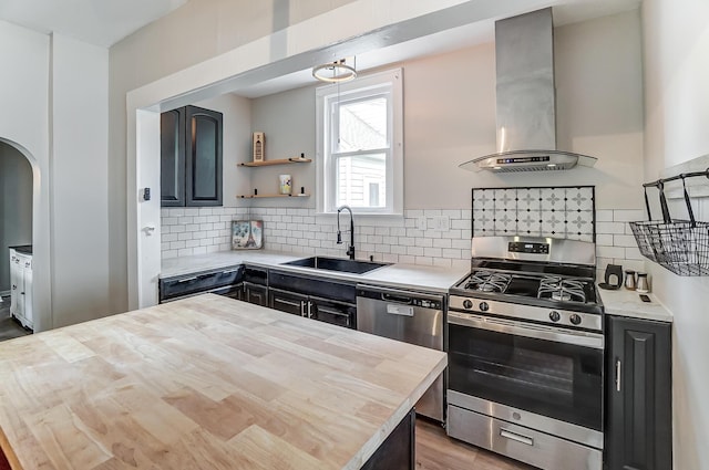 kitchen with stainless steel appliances, sink, island range hood, and wooden counters