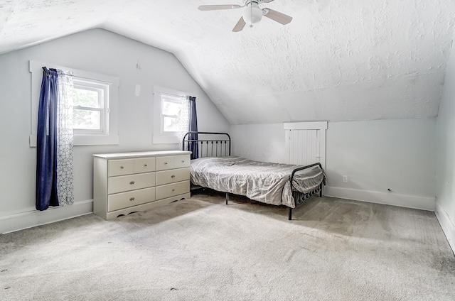 bedroom featuring ceiling fan, vaulted ceiling, light colored carpet, and a textured ceiling