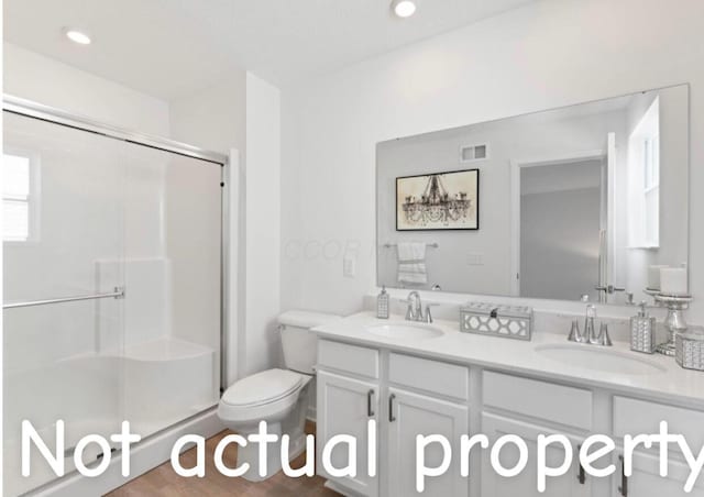 bathroom with hardwood / wood-style floors, vanity, an enclosed shower, and toilet