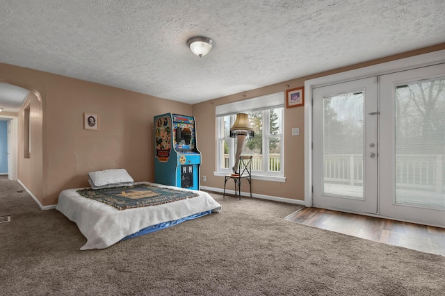 bedroom featuring access to exterior, french doors, a textured ceiling, and hardwood / wood-style flooring