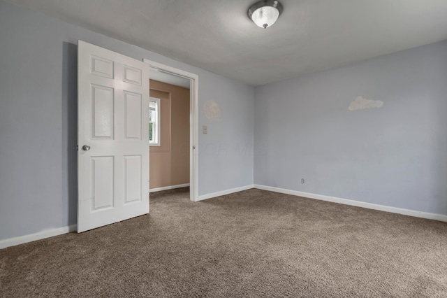 spare room featuring dark colored carpet