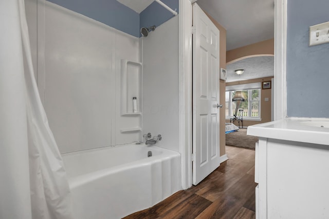 bathroom featuring shower / bathtub combination with curtain, vanity, wood-type flooring, and a textured ceiling