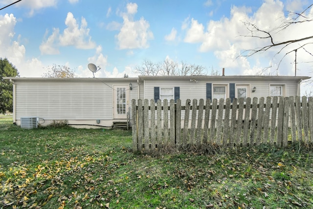 back of house featuring central AC and a lawn