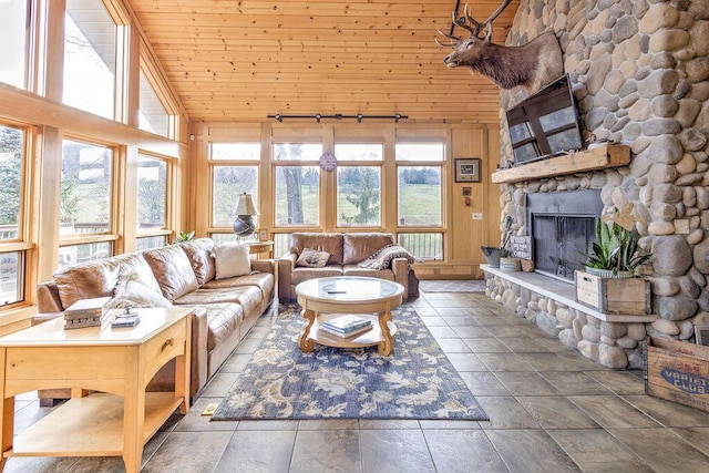 living room with a stone fireplace, wood ceiling, and a high ceiling