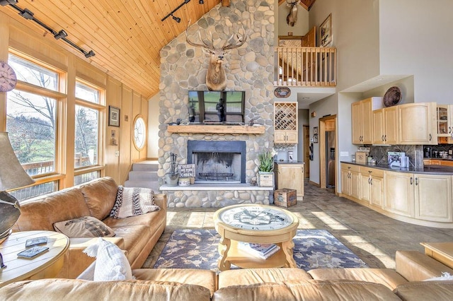 living room with high vaulted ceiling, a stone fireplace, and wood ceiling