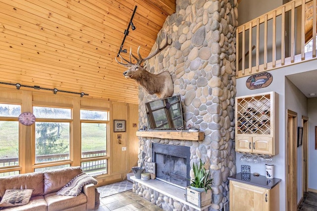 unfurnished living room featuring beam ceiling, high vaulted ceiling, wooden walls, a fireplace, and wood ceiling