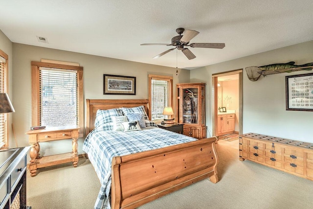 carpeted bedroom featuring ceiling fan, a textured ceiling, and ensuite bath